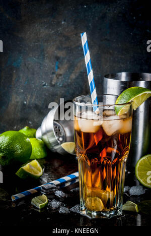 Cuba Libre, long island o tè freddo cocktail con alcool, cola di lime e il ghiaccio, due, Vetro scuro dello sfondo spazio copia Foto Stock