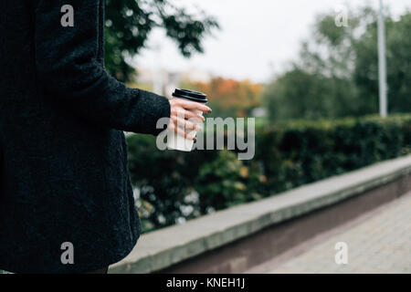 La donna a piedi lungo la strada con un dispositivo monouso tazza da caffè Foto Stock