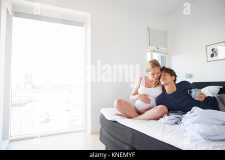 Uomo romantico e incinta ragazza rilassante sul letto Foto Stock