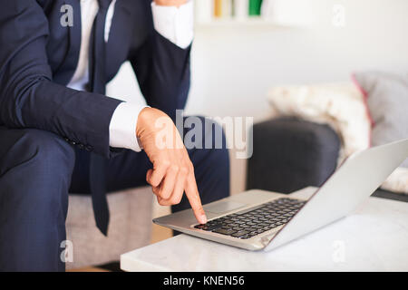 La sezione centrale del proprietario seduto sulla poltrona con laptop Foto Stock