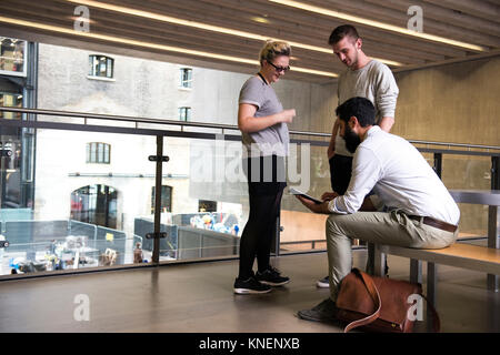 L'uomo con i colleghi sul mezzanino nell edificio per uffici con tavoletta digitale Foto Stock