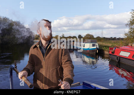 Uomo di fumare e-sigaretta sul canal boat Foto Stock