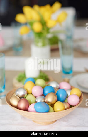 Ciotola di colorate uova di pasqua nella ciotola sul tavolo da pranzo Foto Stock