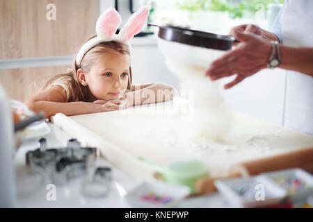 Ragazza Guarda la nonna setacciare la farina per la cottura di pasqua Foto Stock