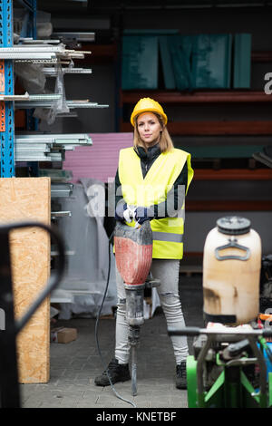 Lavoratore di sesso femminile con jackhammer in una zona industriale. Foto Stock