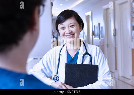 Medico in ospedale a chiacchierare con un collega sorridente Foto Stock