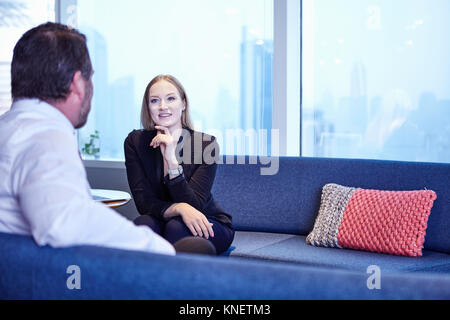I colleghi in ufficio su divani in chat Foto Stock