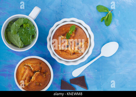 Il cioccolato cupkakes con tè alla menta, sfondo blu, vista dall'alto. Sweet home-cotto concetto. Foto Stock