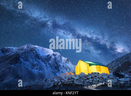 Via Lattea, giallo incandescente tenda e montagne. Incredibile scena con montagna himalayana, cielo stellato di notte in Nepal. Rocce con picco innevato e sky con Foto Stock