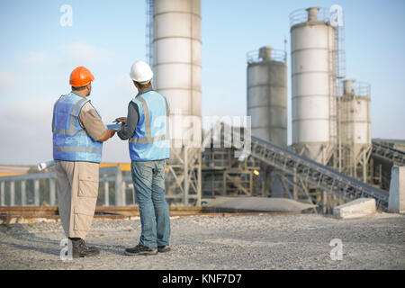 Due lavoratori di cava in discussione, a cava, vista posteriore Foto Stock