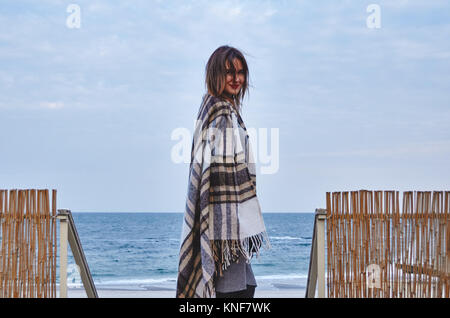 Giovane donna in piedi vicino alla spiaggia, avvolto in una coperta, Odessa, Oblast di Odessa, Ucraina, Europa Foto Stock