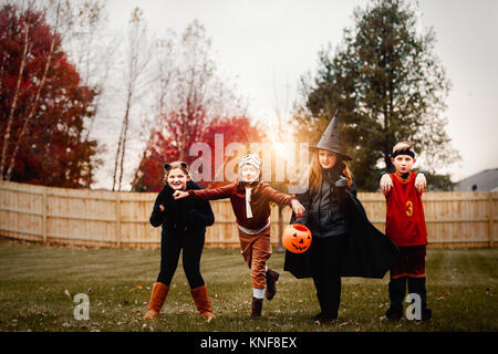 Ritratto di ragazzo e le ragazze poste in costumi di halloween in giardino al tramonto Foto Stock