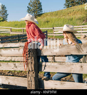 Cowboy e cowgirl indossando il cappello da cowboy appoggiato su di recinzione, guardando lontano, Enterprise, Oregon, Stati Uniti, America del Nord Foto Stock