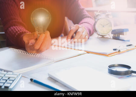 Innovazione o concetto creativo di tenere in mano una lampadina con la calcolatrice. Foto Stock