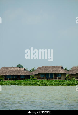 Case dal tetto di paglia lungo il fiume Mekong Foto Stock