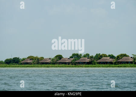 Case dal tetto di paglia lungo il fiume Mekong Foto Stock