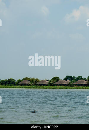 Case dal tetto di paglia lungo il fiume Mekong Foto Stock