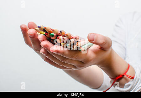 Matite colorate per la verniciatura in bambini con le mani in mano su uno sfondo bianco. Foto Stock