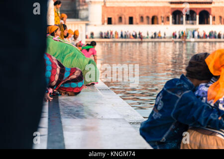 AMRITSAR, India - 20 Marzo 2016: immagine orizzontale delle donne indiane in preghiera di fronte al lago Santo presso Sri Harmandir Sahib, noto come tempio d'oro, Foto Stock