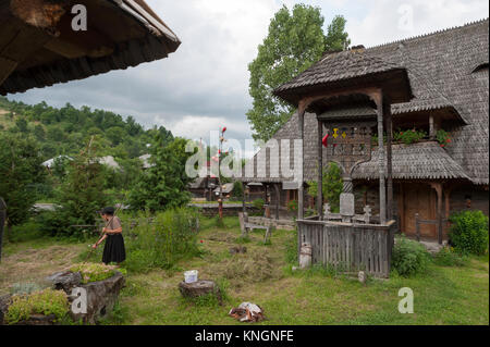 Donna che lavorano nel giardino della sua casa tradizionale in Botiza, Maramureș, Romania. Foto Stock