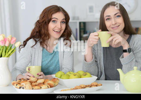 Due femmina sorridente amici seduti a tavola Foto Stock