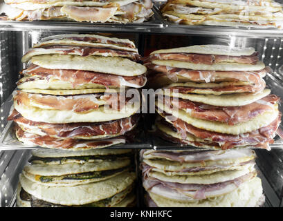 Cibo accatastati in un vetro frontale in frigorifero in un ristorante o una caffetteria con pronta fatta carne fredda panini sul pane piatto Foto Stock