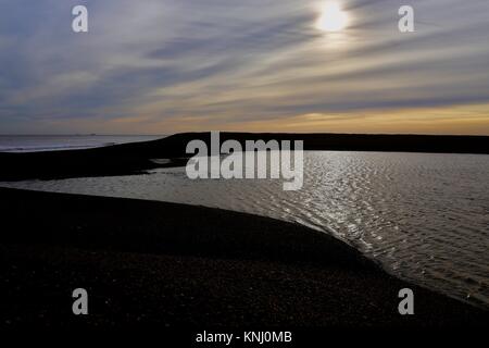 Curva shingle banche intorno ad una laguna salmastra a Shingle Street, Suffolk, Regno Unito. Foto Stock