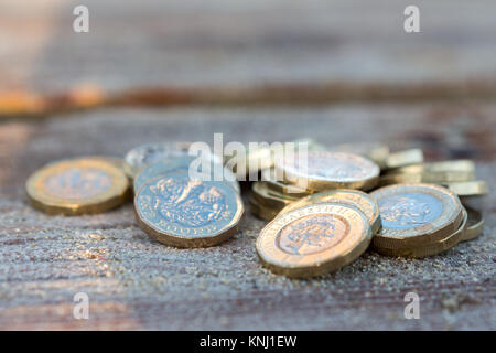 Pila di nuovo British Pound monete sul legno. Nuovo chili in una calda luce di Sunrise. Foto Stock