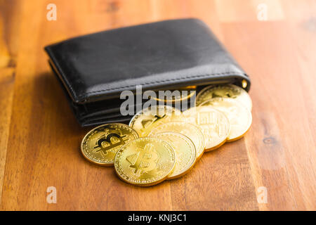 Golden bitcoins in portafoglio in pelle su un tavolo di legno. Foto Stock