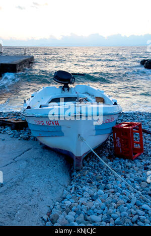 Surf rompe su una piccola barca sulla spiaggia in Kardimyli al tramonto, sulla costa occidentale della Grecia Foto Stock