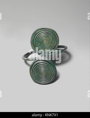 Fascia da braccio dell'età del bronzo europea dal XIV al XII secolo a.C., realizzata in lega di rame con decorazione a spirale, utilizzata come ornamento personale e come esempio di lavorazione dei metalli. Foto Stock