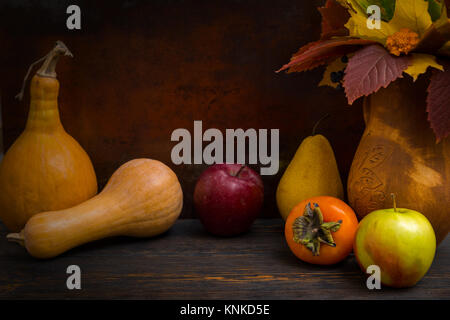 Autunno still life di raccolta delle mele e zucche vicino a foglie in caraffa sulla scrivania in legno. Mockup per offerte stagionali e vacanze post card Foto Stock