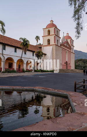 Vista verticale della facciata di Santa Barbara di missione. L'architettura si è riflessa in una fontana vicina. Foto Stock