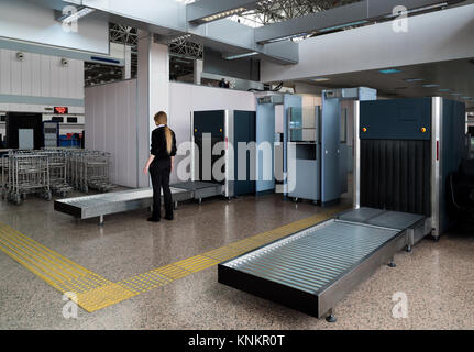 Controllare il bagaglio in aeroporto. Addetto alla sicurezza dell'aeroporto lavora a scanner Foto Stock