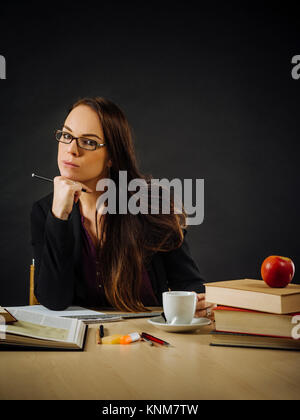 Foto di un insegnante o business donna nel suo 30's seduti ad una scrivania davanti a una grande lavagna. Foto Stock