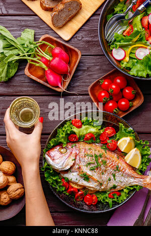 Donna mano afferrando il vino da tavola in legno con piatti colorati Foto Stock