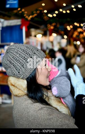 Donna che mantiene il bambino al mercato per le vacanze Foto Stock