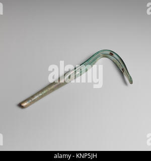 Questo strigil di vetro romano, risalente al III-IV secolo d.C., è realizzato in vetro blu-verde traslucido. È dotato di un lungo manico cilindrico cavo che si espande leggermente verso il basso, con una sezione della lama curva che ha un margine profondo che corre lungo, terminando con una punta arrotondata. La parte superiore dell'impugnatura è rotta e il pezzo mostra segni di agenti atmosferici. Foto Stock