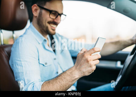 Uomo che utilizza il telefono mentre si guida la macchina Foto Stock