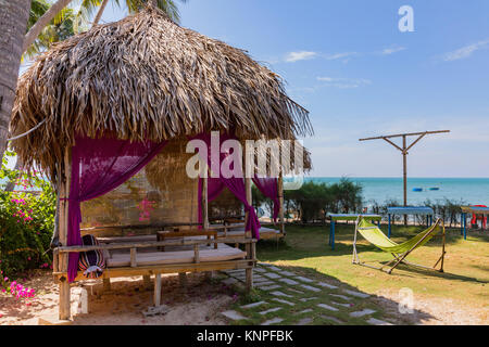 Capanne di bambù in una località sconosciuta. Cottage di legno con lettini sulla spiaggia. Rifugi di appoggio sulla riva, un posto di respirare i rostri. Foto Stock