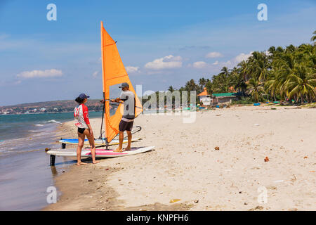 MUI NE, VITNAM - MARZO 24, 2017. Giovane donna e uomo la preparazione per la pratica del windsurf insieme sulla riva. Foto Stock