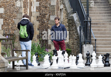 Unknown giovani uomini giocare a scacchi su una scheda esterna, situata nel cortile/parco al di fuori della Cattedrale di Southwark, Londra Foto Stock
