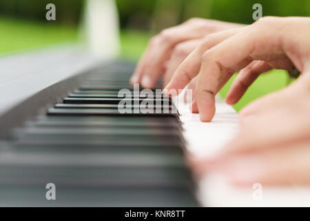Due persone irriconoscibili suonare il pianoforte in piedi sull'erba. Foto Stock