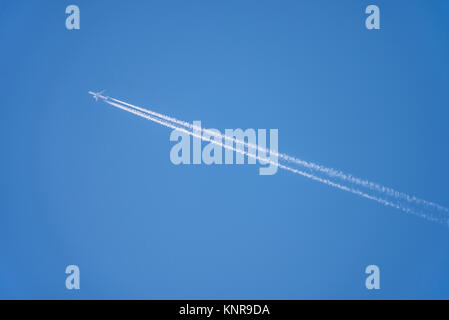 Contrails. Aereo di linea jet che vola in quota lasciando contrasta le tracce di vapore in altezza nel cielo blu. Tracce di vapore Foto Stock