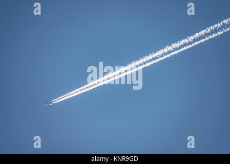 Contrails. Aereo di linea jet che vola in quota lasciando contrasta le tracce di vapore in altezza nel cielo blu. Tracce di vapore Foto Stock