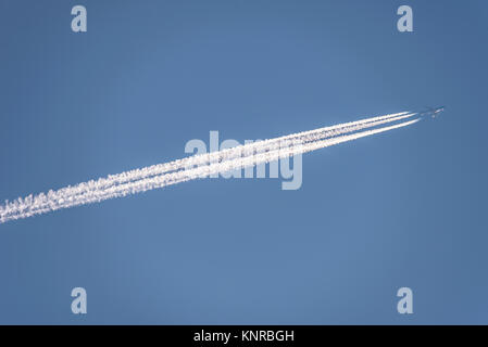 Contrails. Aereo di linea jet che vola ad altitudine lasciando tracce di vapore di contrail in altezza nel cielo blu. Tracce di vapore Foto Stock