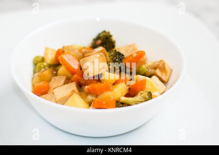 Verdure cotte con tofu in vaso bianco Foto Stock