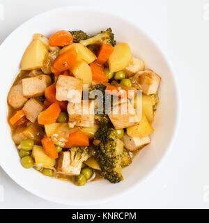 Verdure cotte con tofu in bianco ciotola. Vista dall'alto in basso sul piatto Foto Stock