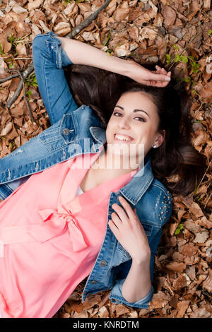 Junge Frau liegt im Laub - donna giacente in foglie Foto Stock