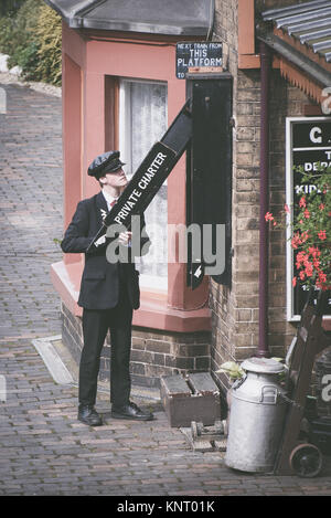 Un uomo cambiare la carta privato segno a Arley stazione ferroviaria Foto Stock